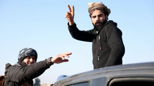 شخصان يلوحان بيديهما في منطقة مفتوحة، مع خلفية واضحة للسماء الزرقاء، في سياق التطورات العسكرية في دير الزور.