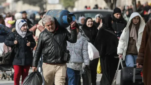 مشهد لمدنيين في حلب يحملون أمتعتهم، مع تصاعد التوترات والعنف في المدينة، حيث يسعون للفرار من الأحياء الكردية.