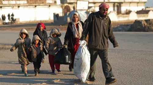 عائلة سورية تتنقل في منطقة نائية، حيث تظهر الأم مع أطفالها يحملون أكياساً، مما يعكس الظروف الصعبة التي يواجهها النازحون في شمال سوريا.