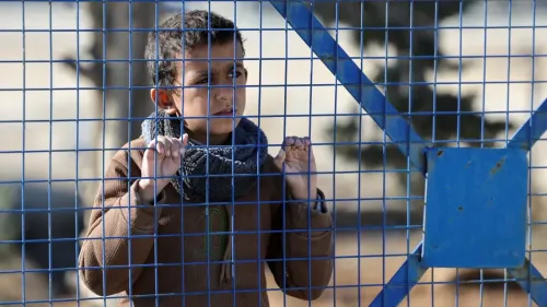 طفل ينظر من خلال سياج معدني في مخيم الهول، حيث تم إخلاء المحتجزين الأجانب بعد نقل المسؤولية إلى الحكومة السورية.