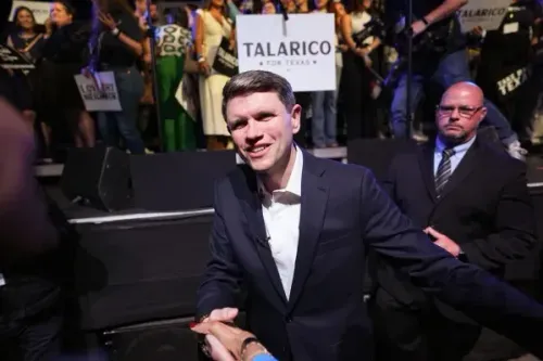 جيمس تالاريكو يحيي أنصاره في احتفاله بفوز الانتخابات التمهيدية، مع لافتات "تالاريكو لتكساس" في الخلفية، وسط حشد متحمس.