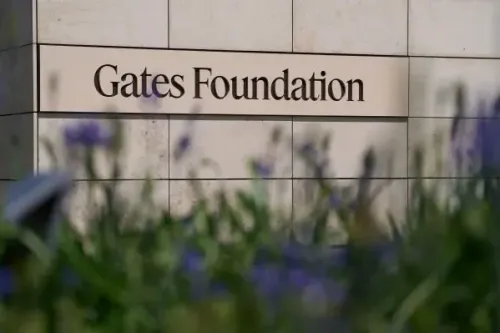 مؤسسة Gates تظهر في الصورة، مع التركيز على اسمها المكتوب بوضوح، محاطة بأزهار خضراء، مما يعكس جهودها في الصحة العالمية والتنمية.