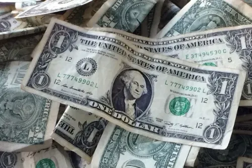 تكدس من الدولارات الأمريكية، مع التركيز على ورقة الدولار الواحد، مما يعكس موضوع الاستثمار والمالية في المقال.