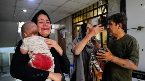 امرأة تبكي وهي تحمل طفلاً مصاباً، بينما يظهر شخص آخر متأثراً بالدماء، في مشهد يعكس معاناة المدنيين في النزاع.