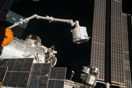 الذراع الآلي الكندي Canadarm2 معلق على محطة الفضاء الدولية، يبرز تعطل الذراع الذي يؤثر على عمليات الشحن والصيانة في المحطة.