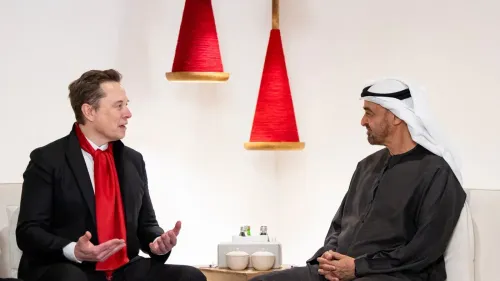 محادثة بين رجلين، أحدهما يرتدي بدلة رسمية مع ربطة عنق حمراء، والآخر يرتدي الزي الإماراتي التقليدي، في مكان ذو ديكور بسيط.