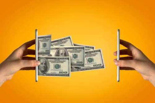 يدان تمسكان بهاتفين ذكيين يتدفق منهما أوراق نقدية من فئة 100 دولار، تعبيراً عن ارتفاع تكلفة تصنيع الهواتف الذكية بالكامل في أمريكا.
