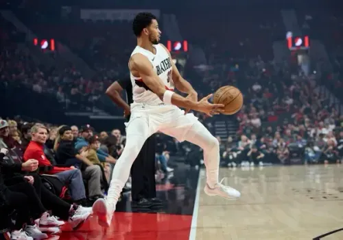 لاعب بورتلاند تريل بليزرز سكوت هندرسون يستعد لتمرير الكرة خلال مباراة، مع مشجعين في الخلفية.