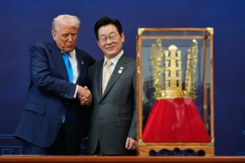 ترامب وشي جين بينغ يتصافحان خلال قمة في بوسان، مع تمثال ذهبي خلفهما، مما يعكس أهمية العلاقات التجارية بين الولايات المتحدة والصين.