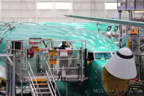 طائرة Boeing 737 Max قيد التجميع في المصنع، مع وجود عامل على المنصة، في سياق صفقة طائرات مع الصين تشمل 200 طائرة.