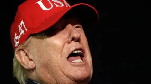 تصوير للرئيس الأمريكي دونالد ترامب وهو يتحدث بحماس، مرتديًا قبعة حمراء تحمل شعار "USA"، مع تعبيرات وجه تعكس الجدية في حديثه عن القضايا السياسية.