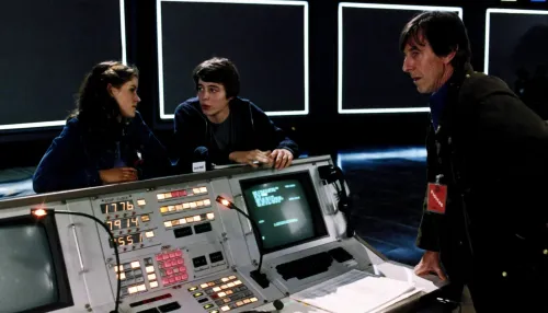 مشهد من فيلم "WarGames" يظهر مراهقين أمام حاسوب قديم يناقشون لعبة فيديو تحاكي حرباً نووية، يعكس مخاوف الذكاء الاصطناعي والدفاع الأمريكي.
