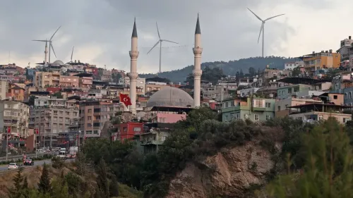 منظر لمدينة دورتيول في تركيا، يظهر مئذنة مسجد، مباني ملونة، وعلم تركي، مع توربينات رياح في الخلفية تعكس التقدم التكنولوجي.