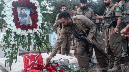 مقاتلون أكراد يضعون وروداً على قبر مغطى بعلم حزب العمال الكردستاني PKK في مراسم تأبين تعكس التوترات الإقليمية بين تركيا وإيران.