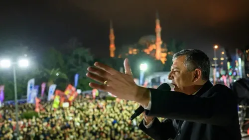 تجمع حاشد لمؤيدي حزب الشعب الجمهوري في تركيا، حيث يتحدث أحد القادة أمام الجمهور في أجواء مشحونة، مع معالم تاريخية مضاءة في الخلفية.