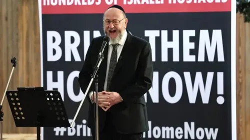 الحاخام الأكبر البريطاني إفرايم ميرفيس يتحدث في حدث، مع لافتة تطالب بإعادة المحتجزين الإسرائيليين، في سياق الجدل حول مؤتمر معاداة السامية.