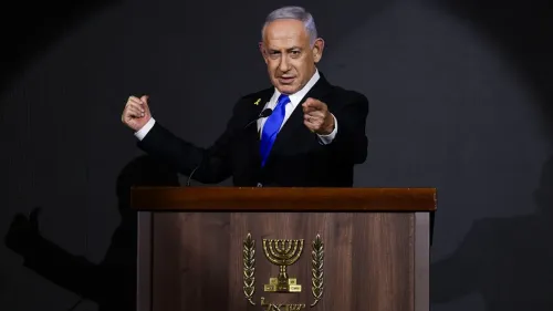 رئيس الوزراء الإسرائيلي بنيامين نتنياهو يتحدث من منصة رسمية، محاطاً بإضاءة خافتة، مع إيماءات تعبر عن التأكيد والسلطة.