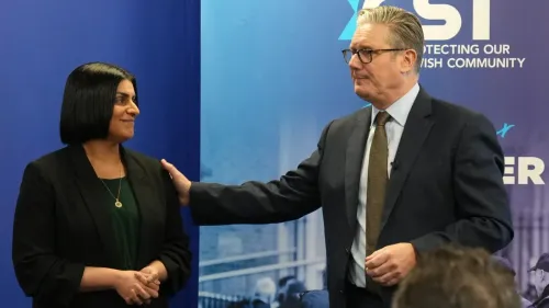 وزيرة الداخلية البريطانية شابانا محمود تتحدث مع مسؤول خلال فعالية، مع خلفية تعكس اهتمام الحكومة بحماية المجتمع اليهودي.
