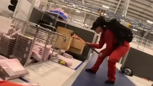 ناشط يرتدي زيًا أحمر ويستخدم مطرقة لتدمير المعدات داخل منشأة تصنيع أسلحة، في سياق احتجاج ضد شركة إسرائيلية.