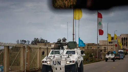 قوة الأمم المتحدة تسير في قافلة عسكرية في لبنان، مع وجود أعلام لبنان وأعلام أخرى، تعبيرًا عن جهود الاستقرار في المنطقة.