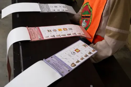 موظف انتخابي في زامبيا يرتدي سترة برتقالية يعرض أوراق الاقتراع خلال انتخابات مضطربة أثارت قلق حقوق الإنسان.