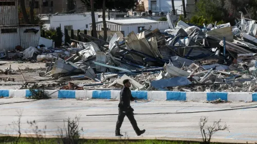 حطام مبنى وكالة الأونروا في حي الشيخ جراح بالقدس بعد الهجوم، مع وجود شخص يمشي في الموقع. يشير الحادث إلى التوترات المستمرة في المنطقة.