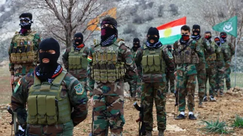 مقاتلون من البيشمركة الكردية يرتدون زيًا عسكريًا ويستعدون لمواجهة التهديدات الإيرانية، مع الأعلام الكردية في الخلفية.