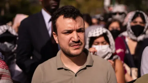 محمود خليل، الناشط الفلسطيني، يظهر في تجمع احتجاجي، مع تعبير جاد، وسط حشد من المتظاهرين الذين يرتدون الكمامات.