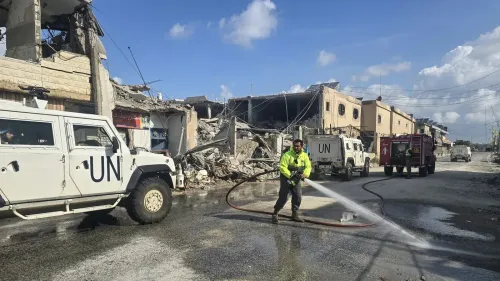 رجال إطفاء من الأمم المتحدة يعملون على إخماد حريق في منطقة مدمرة، مع وجود مركبات تابعة للأمم المتحدة في الخلفية.