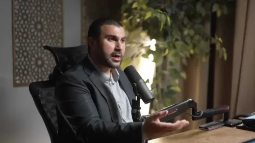 سامي حمدي، الصحفي المؤيد لفلسطين، يتحدث بإلحاح أثناء مقابلة، مع خلفية نباتية، معبراً عن قضايا حقوق الإنسان وحرية التعبير.