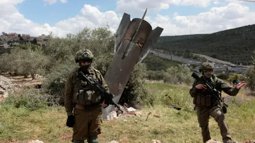 جنود إسرائيليون يقفون بجانب حطام صاروخ في منطقة جبلية، مما يعكس التوترات العسكرية مع إيران وتأثيرها على الأمن الإقليمي.