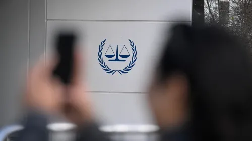 شعار المحكمة الجنائية الدولية على جدار خارجي مع أشخاص يلتقطون صورًا، في سياق العقوبات الأمريكية المثيرة للجدل ضد المحكمة ومنظمات حقوق الإنسان.