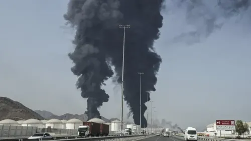 دخان أسود كثيف يتصاعد من منشأة نفطية في الشرق الأوسط، مما يعكس تصاعد التوترات والأزمات الإقليمية.