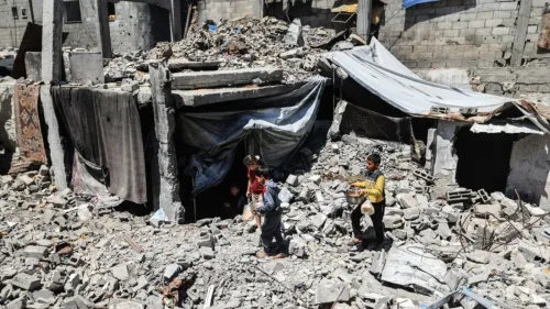 أطفال فلسطينيون يتجولون بين أنقاض مبنى مدمر في غزة، مع وجود خيام وأقمشة لتوفير الحماية في ظل الظروف الصعبة.