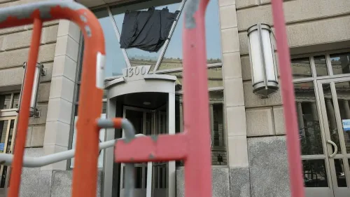 مدخل مبنى حكومي في واشنطن، مع وجود حواجز أمنية وقطعة قماش سوداء معلقة على الواجهة، تعكس أجواء التوتر السياسي.