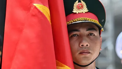 جندي فيتنامي يحمل العلم الوطني، يعكس التزام البلاد بالتاريخ العسكري ودعم فلسطين في سياق العلاقات الدولية المتغيرة.