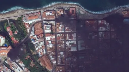 دخان كثيف يغطي مدينة بويرتو فالارتا المكسيكية بعد أعمال عنف، مع تضرر المباني والسيارات، مما يعكس حالة الفوضى في المنطقة.