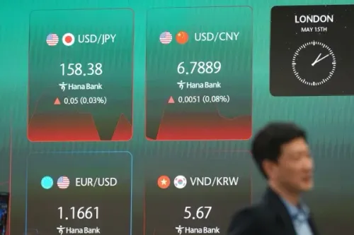 شاشة تعرض أسعار صرف العملات الأجنبية، بما في ذلك الدولار الأمريكي مقابل الين الياباني واليوان الصيني، مع شخص يمشي في الخلفية.