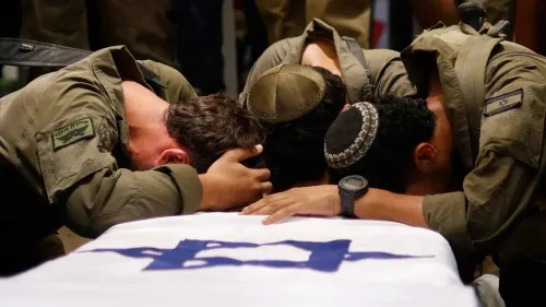 جنود إسرائيليون يعبّرون عن حزنهم أثناء تأبين زميل لهم، مع العلم الوطني ممدود تحتهم، في سياق ارتفاع حالات الانتحار بين الجنود.