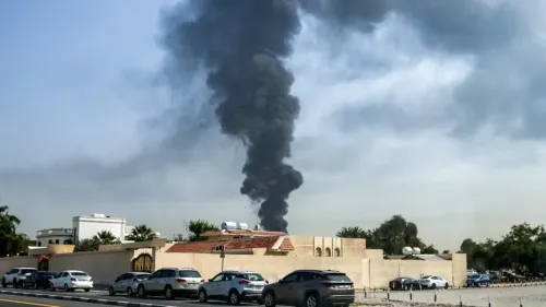 تصاعد دخان كثيف من موقع حريق في دبي، مع وجود سيارات متوقفة على جانب الطريق، مما يعكس تأثير الحرب على المدينة.