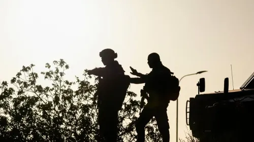 جنديان إسرائيليان في نقطة تفتيش بالضفة الغربية عند الغروب، يعكسان القيود الأمنية التي تؤثر على حركة العمال الفلسطينيين.