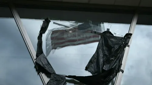 شباك مكسور يظهر علم الوكالة الأمريكية للتنمية الدولية (USAID) مغطى بغطاء أسود، مما يعكس تأثير تخفيضات المساعدات الإنسانية.