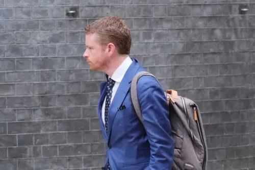 مورغان مكسويني، رئيس موظفي داونينج ستريت، يسير مرتديًا بدلة زرقاء ويحمل حقيبة ظهر، وسط أجواء من التوتر السياسي في بريطانيا.