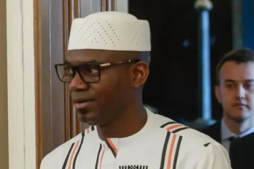 رجل يرتدي زيًا تقليديًا مع قبعة بيضاء ونظارات، يظهر في مكان رسمي، مما يعكس الأجواء السياسية في مالي وسط تصاعد التوترات الأمنية.