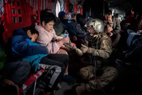 جنود يساعدون أطفالًا نازحين في طائرة عسكرية، حيث يتم تقديم المياه والدعم أثناء عملية الإجلاء من القرى المتضررة في ألاسكا.