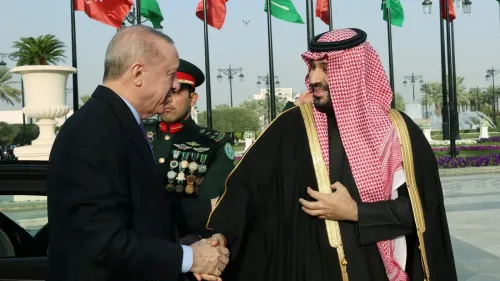 زيارة الرئيس التركي رجب طيب أردوغان إلى السعودية، حيث يتصافح مع ولي العهد محمد بن سلمان، وسط أعلام الدول في الخلفية.