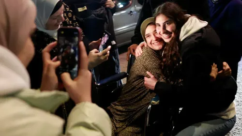 احتفال عائلي مؤثر عند عودة الأسرى الفلسطينيين، مع عناق بين امرأة على كرسي متحرك وفتاة، وسط مشاعر الفرح والتواصل.