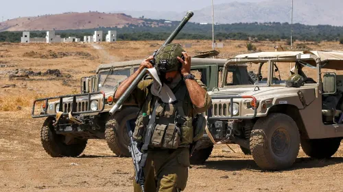 جندي إسرائيلي يرتدي خوذة ويحمل سلاحًا، يقف في منطقة جرداء قرب مركبات عسكرية، مشيرًا إلى التوترات المتزايدة في مرتفعات الجولان.