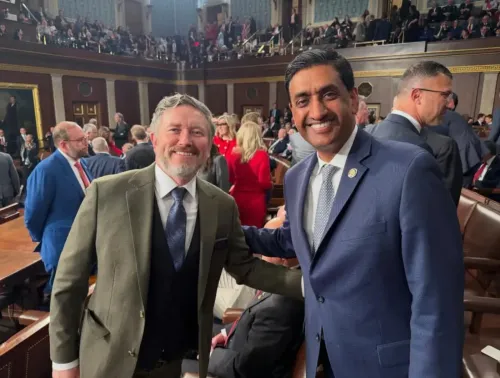 عضو الكونغرس رو خانا وعضو الكونغرس توماس ماسي يتصافحان في قاعة مجلس النواب خلال خطاب حالة الاتحاد، مع خلفية من الحضور.