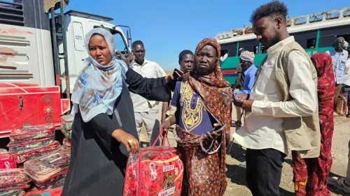 نساء ورجال في منطقة توزيع المساعدات الإنسانية بالسودان، يعكسون تأثير الحرب المستمر على الحياة اليومية والاحتياجات الملحة.